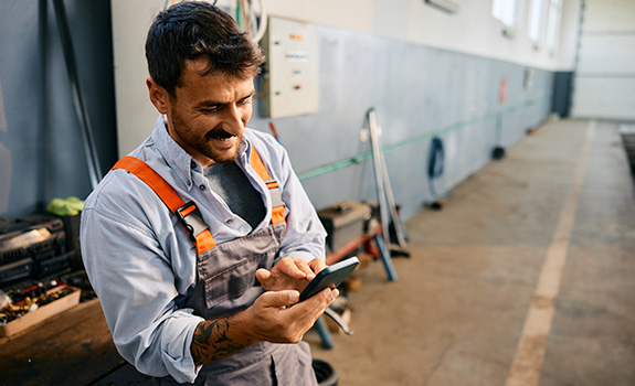 Happy tradesperson on mobile phone while working in a workshop