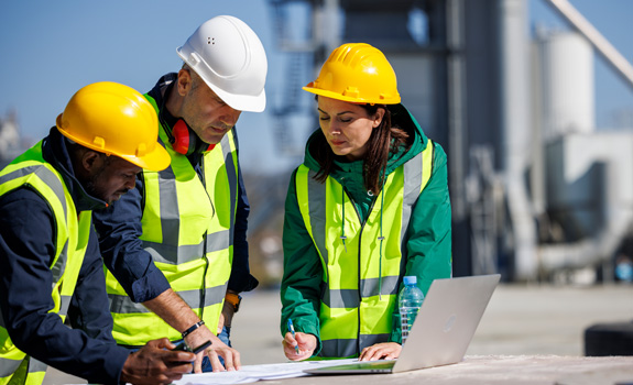 Three service providers on construction site looking at laptop